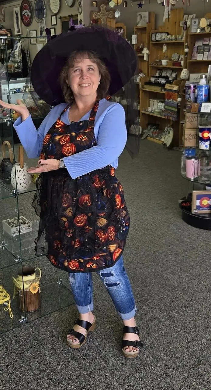 A woman in an apron is standing inside of a store.