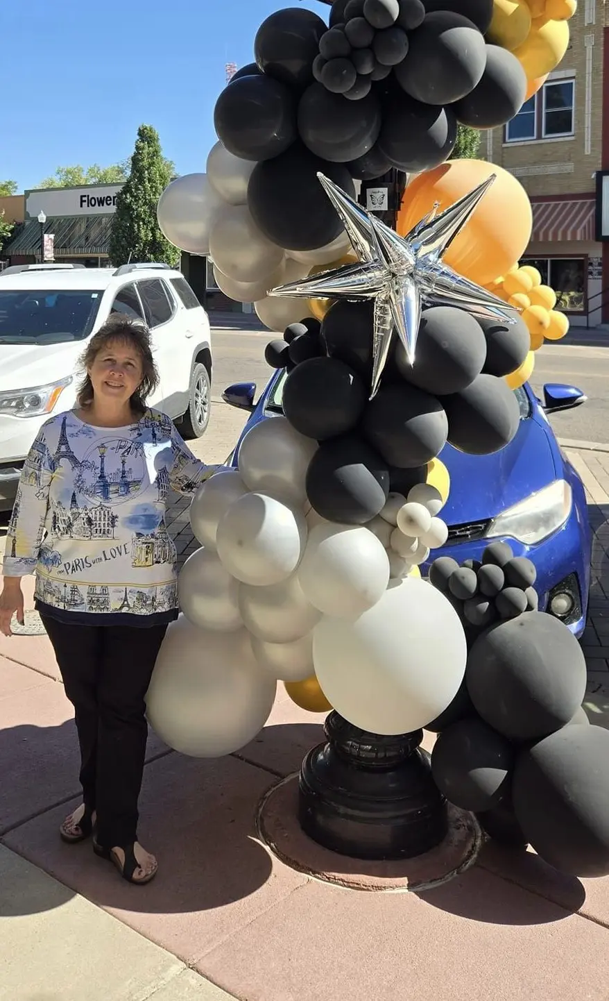 A woman standing next to balloons on the street.