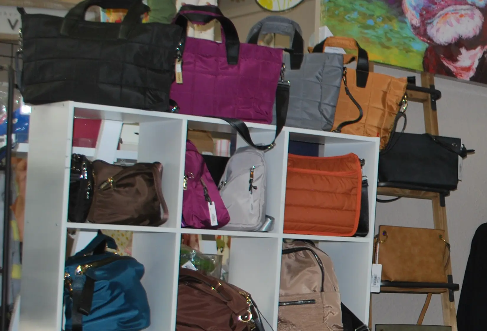 A wall of purses and bags in a closet.